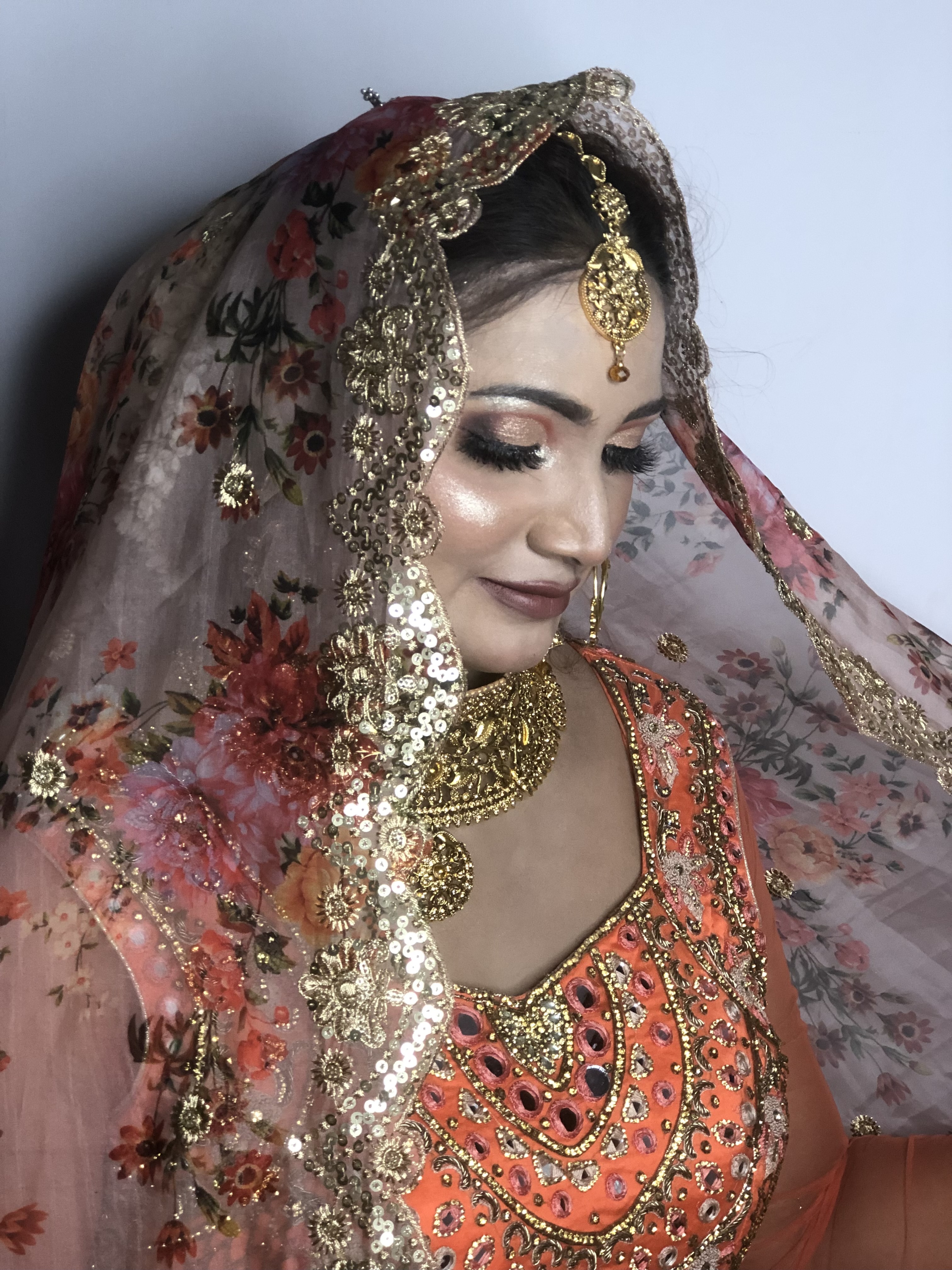 Asian bridal makeup in orange lehenga with dramatic lighting